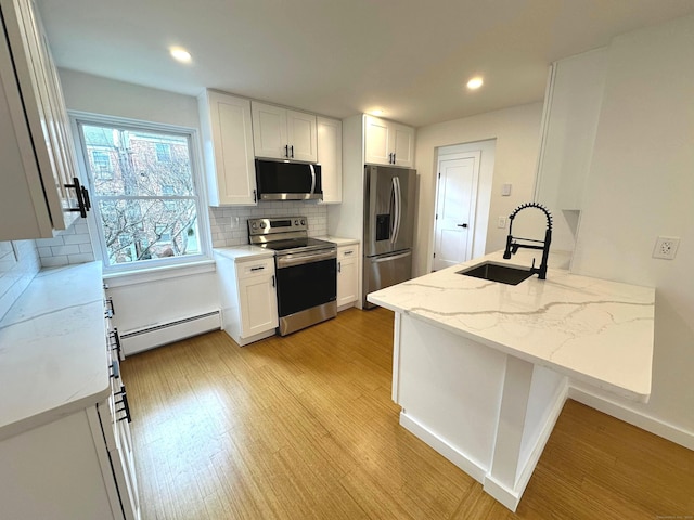 kitchen with light stone counters, stainless steel appliances, baseboard heating, sink, and white cabinetry