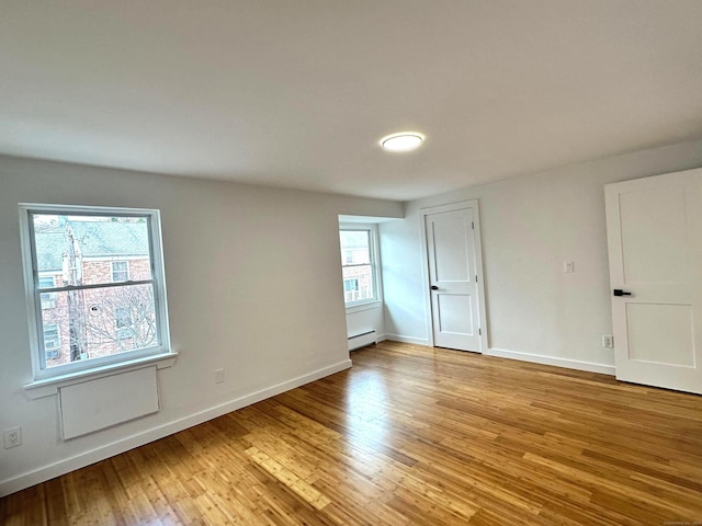 unfurnished room with light wood-type flooring and a baseboard radiator