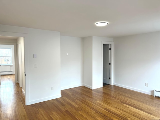 unfurnished room featuring wood-type flooring and a baseboard heating unit