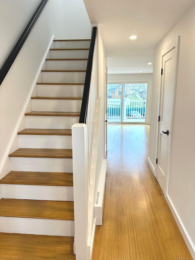 stairway with hardwood / wood-style floors and a baseboard radiator