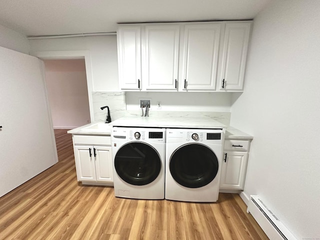 laundry room with cabinets, a baseboard heating unit, sink, independent washer and dryer, and light hardwood / wood-style floors