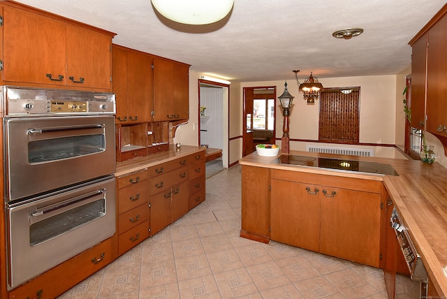 kitchen featuring wood counters, stainless steel double oven, a notable chandelier, stovetop, and hanging light fixtures