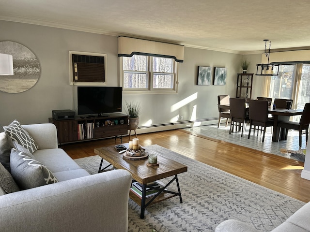 living area with a baseboard heating unit, an AC wall unit, crown molding, and wood finished floors