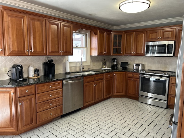 kitchen featuring tasteful backsplash, appliances with stainless steel finishes, brown cabinets, dark stone countertops, and a sink