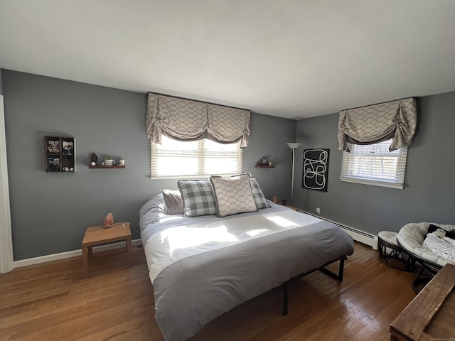 bedroom featuring multiple windows, baseboards, and wood finished floors