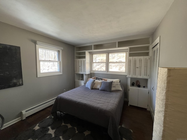 bedroom featuring a baseboard heating unit, baseboards, and wood finished floors