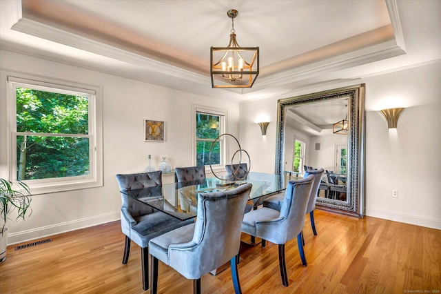 dining area featuring a chandelier, light wood-type flooring, and a tray ceiling