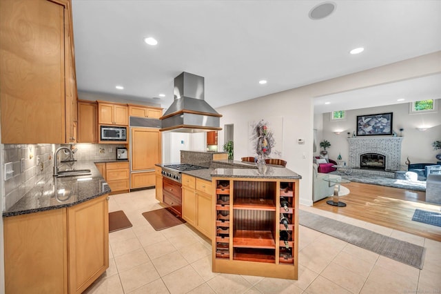 kitchen featuring built in microwave, sink, dark stone countertops, light tile patterned flooring, and custom range hood