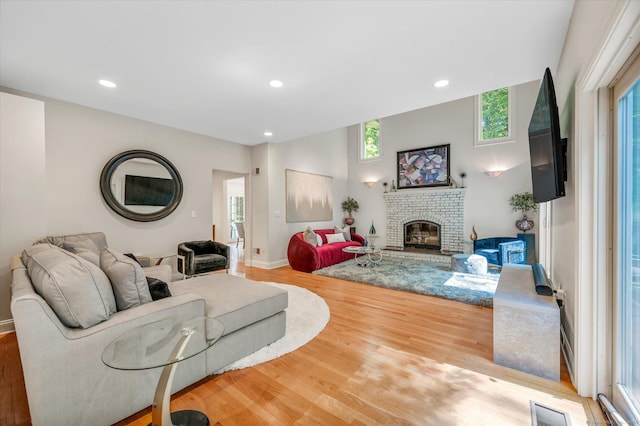 living room featuring light wood-type flooring and a brick fireplace