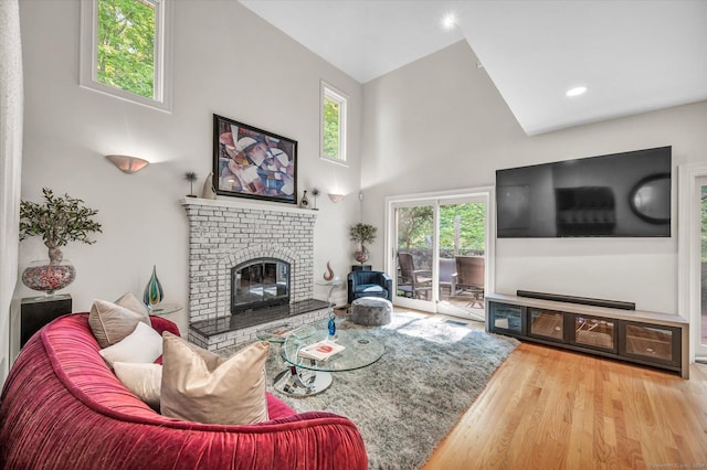 living room with a fireplace, wood-type flooring, and high vaulted ceiling