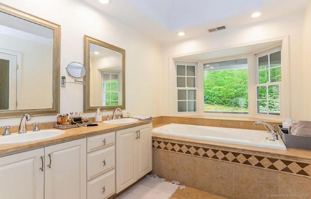 bathroom featuring tile patterned flooring, a relaxing tiled tub, and vanity