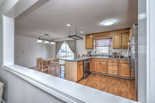 kitchen featuring sink, hanging light fixtures, light hardwood / wood-style flooring, stainless steel dishwasher, and kitchen peninsula