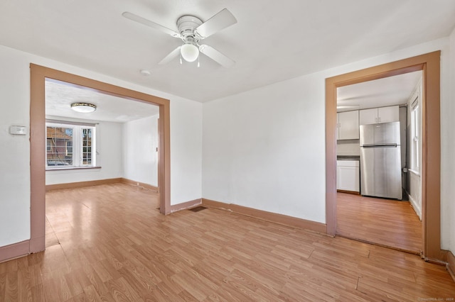 empty room with ceiling fan and light hardwood / wood-style flooring