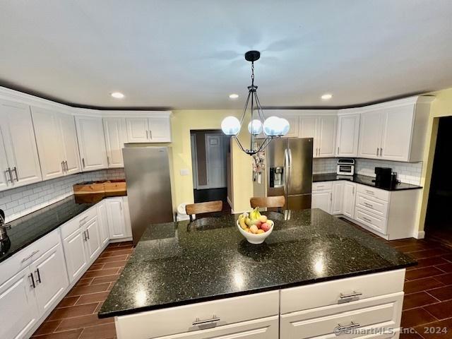 kitchen featuring a center island, freestanding refrigerator, wood tiled floor, white cabinets, and stainless steel fridge with ice dispenser