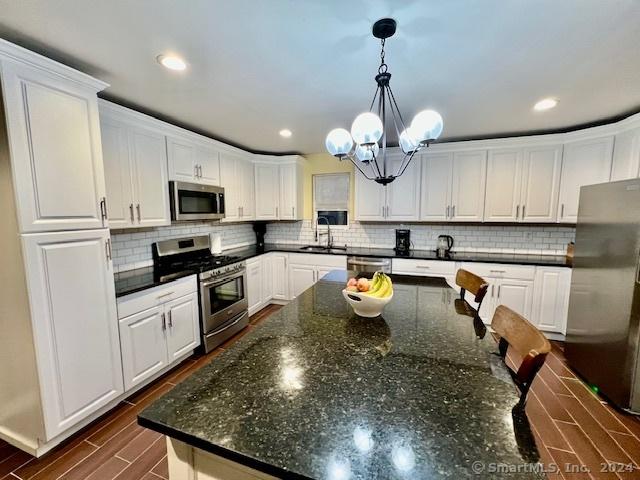 kitchen with stainless steel appliances, a sink, white cabinetry, and pendant lighting