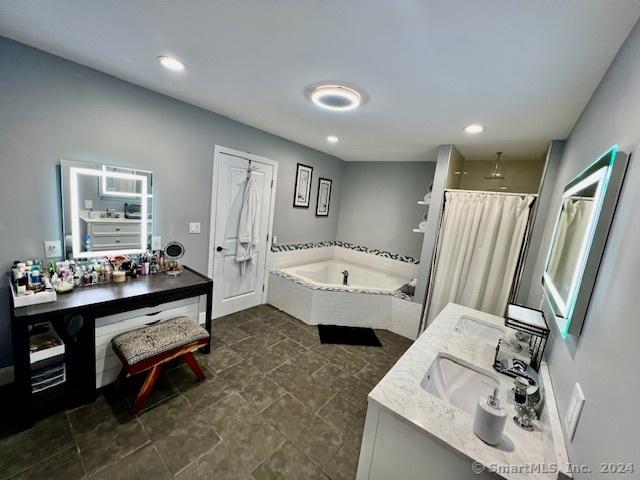 bathroom with double vanity, a shower with shower curtain, a garden tub, a sink, and recessed lighting