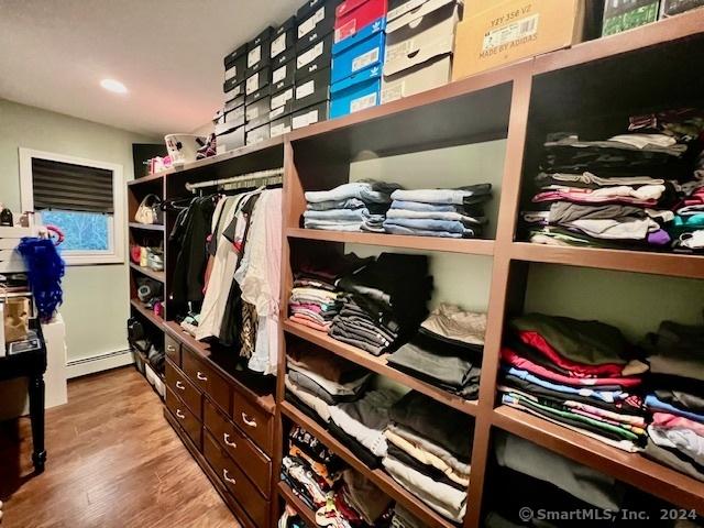 walk in closet with light wood-type flooring and baseboard heating