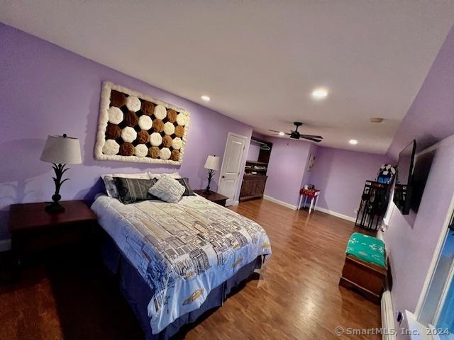 bedroom with baseboard heating, recessed lighting, wood finished floors, and baseboards