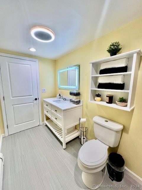 bathroom with baseboards, vanity, and toilet