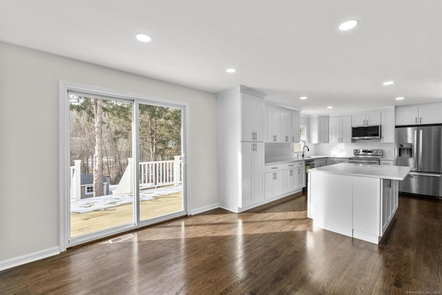 kitchen featuring dark wood-type flooring, sink, white cabinetry, a center island, and appliances with stainless steel finishes