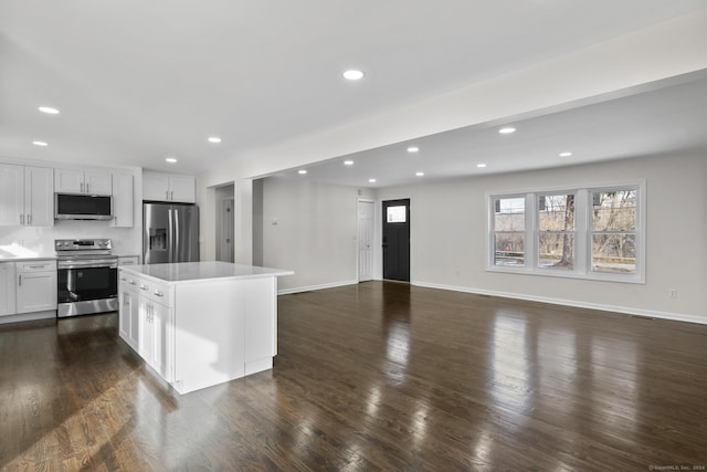 kitchen featuring a kitchen island, appliances with stainless steel finishes, tasteful backsplash, white cabinets, and dark wood-type flooring