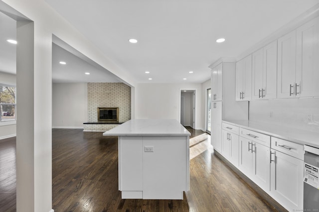 kitchen featuring dark hardwood / wood-style flooring, light stone countertops, white cabinets, and a kitchen island