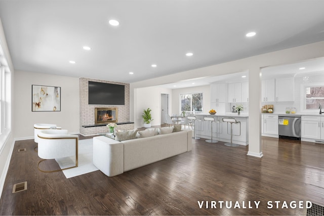 unfurnished living room with dark hardwood / wood-style flooring and a brick fireplace