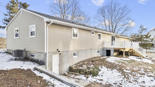 snow covered property featuring cooling unit and a wooden deck