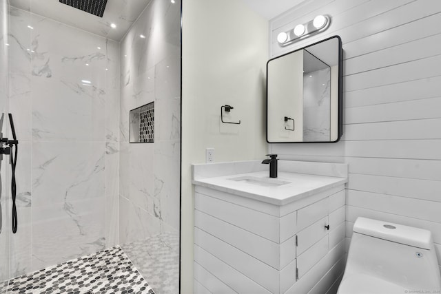 bathroom featuring vanity, tiled shower, wood walls, and toilet