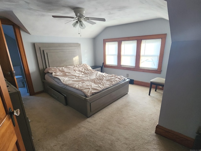 carpeted bedroom with connected bathroom, ceiling fan, and lofted ceiling