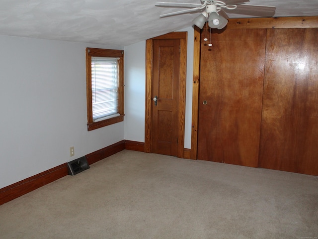 carpeted empty room with ceiling fan and lofted ceiling