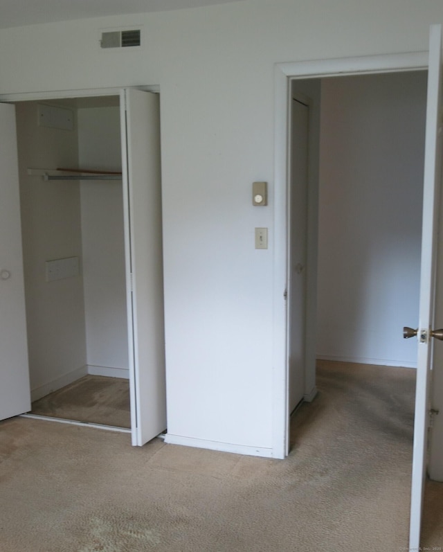 unfurnished bedroom featuring a closet and light colored carpet