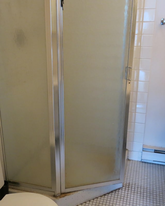 bathroom featuring toilet, tile patterned floors, a baseboard heating unit, and an enclosed shower