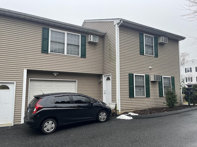 view of front of home featuring a garage and a wall unit AC