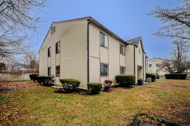 view of side of property with central AC unit and a yard