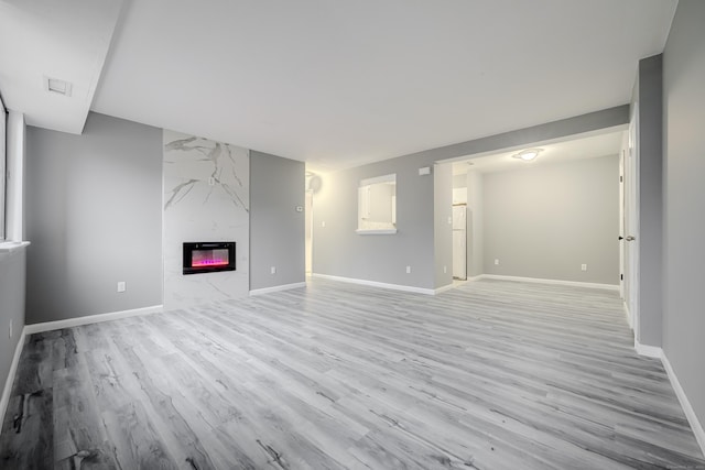 unfurnished living room featuring light wood-type flooring and a high end fireplace