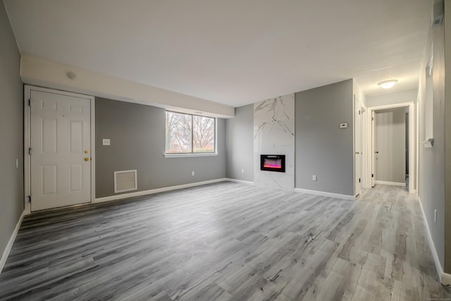 unfurnished living room with a premium fireplace and light hardwood / wood-style flooring