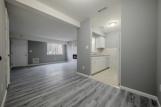 unfurnished living room with a textured ceiling and light hardwood / wood-style flooring