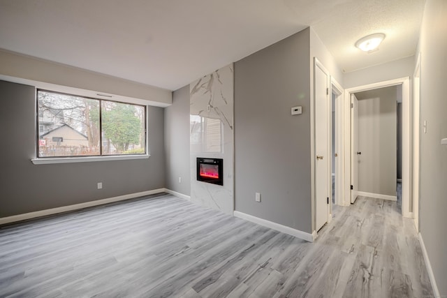 empty room with a fireplace and light hardwood / wood-style flooring