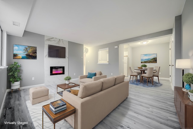 living room with a high end fireplace and light hardwood / wood-style floors