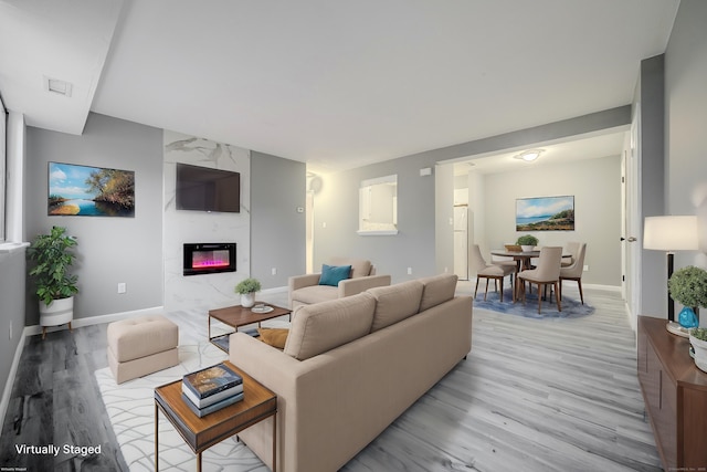 living room featuring a high end fireplace and light hardwood / wood-style flooring