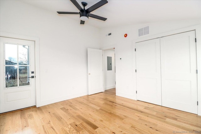 unfurnished bedroom featuring lofted ceiling, electric panel, light hardwood / wood-style flooring, ceiling fan, and a closet