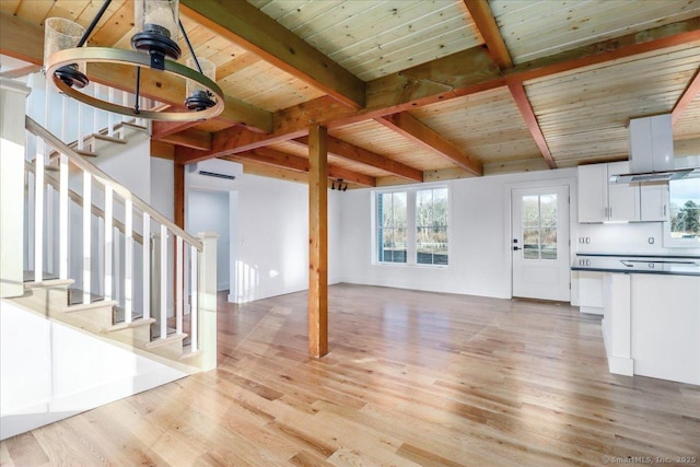 unfurnished living room featuring beam ceiling, light wood-type flooring, an AC wall unit, and wooden ceiling