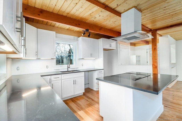 kitchen with cooktop, island range hood, white cabinetry, and sink