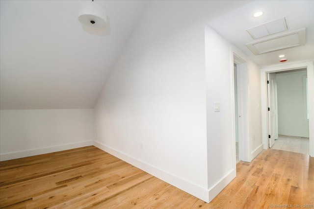 additional living space featuring light wood-type flooring and vaulted ceiling