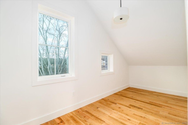 additional living space with hardwood / wood-style floors and vaulted ceiling