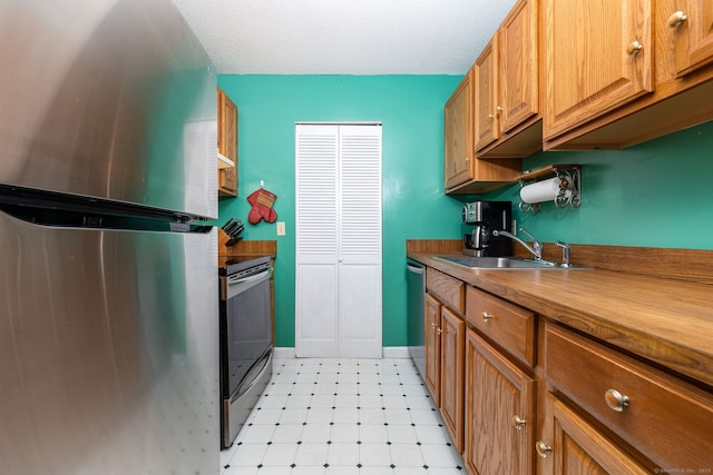 kitchen featuring stainless steel appliances, a textured ceiling, and sink