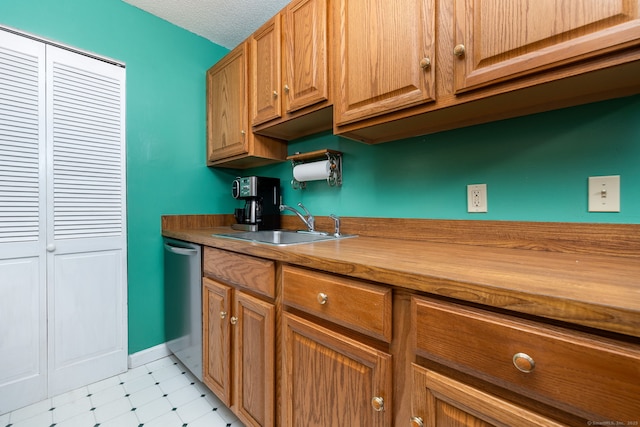 kitchen featuring stainless steel dishwasher, a textured ceiling, and sink