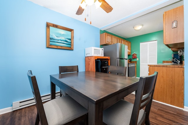 dining area with baseboard heating, ceiling fan, dark hardwood / wood-style flooring, and sink