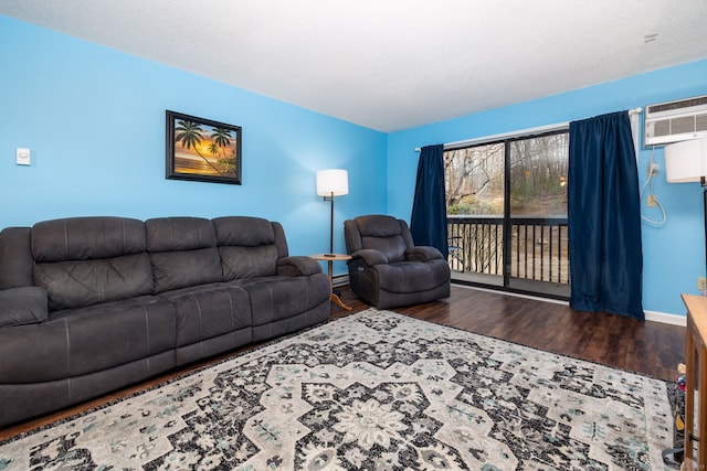 living room featuring a textured ceiling, a wall unit AC, and dark hardwood / wood-style floors